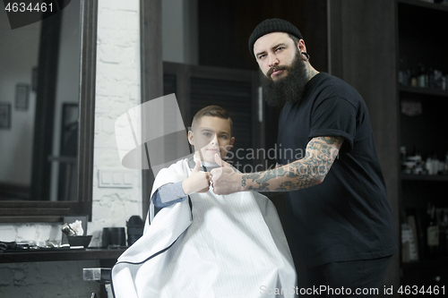 Image of Children hairdresser cutting little boy against a dark background.