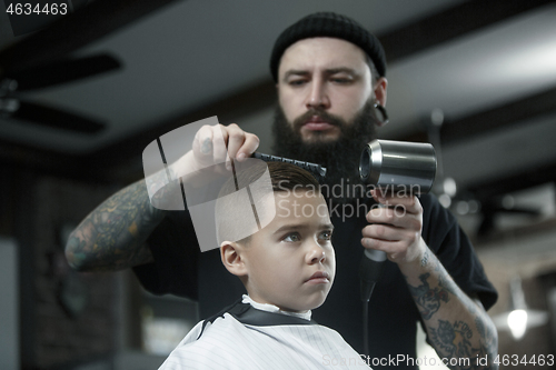 Image of Children hairdresser cutting little boy against a dark background.