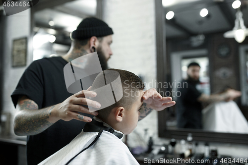 Image of Children hairdresser cutting little boy against a dark background.