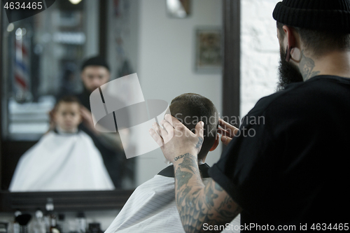 Image of Children hairdresser cutting little boy against a dark background.