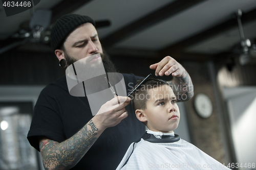 Image of Children hairdresser cutting little boy against a dark background.