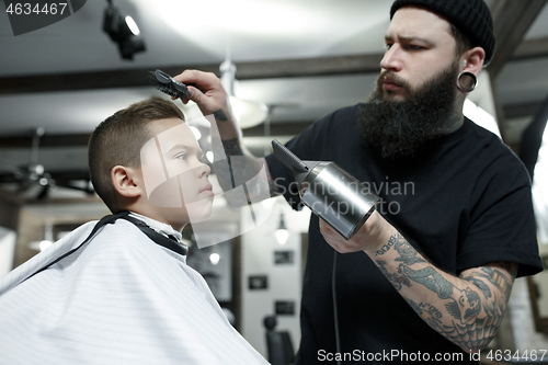 Image of Children hairdresser cutting little boy against a dark background.