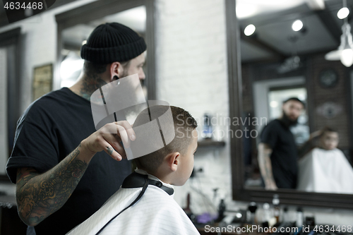 Image of Children hairdresser cutting little boy against a dark background.