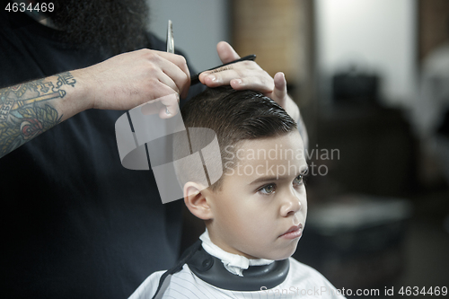 Image of Children hairdresser cutting little boy against a dark background.