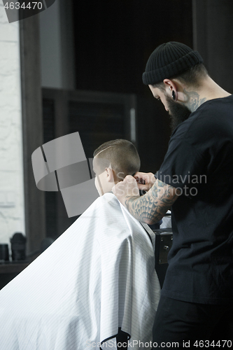 Image of Children hairdresser cutting little boy against a dark background.