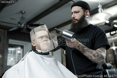 Image of Children hairdresser cutting little boy against a dark background.