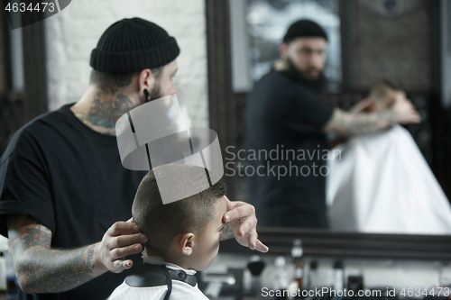 Image of Children hairdresser cutting little boy against a dark background.