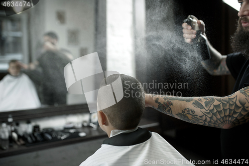 Image of Children hairdresser cutting little boy against a dark background.