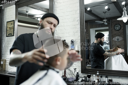 Image of Children hairdresser cutting little boy against a dark background.