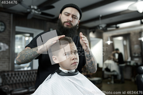 Image of Children hairdresser cutting little boy against a dark background.