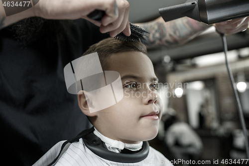 Image of Children hairdresser cutting little boy against a dark background.