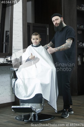 Image of Children hairdresser cutting little boy against a dark background.