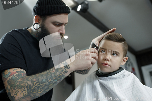 Image of Children hairdresser cutting little boy against a dark background.