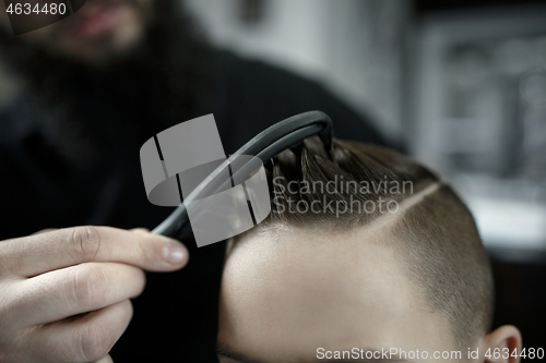 Image of Children hairdresser cutting little boy against a dark background.