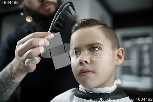 Image of Children hairdresser cutting little boy against a dark background.