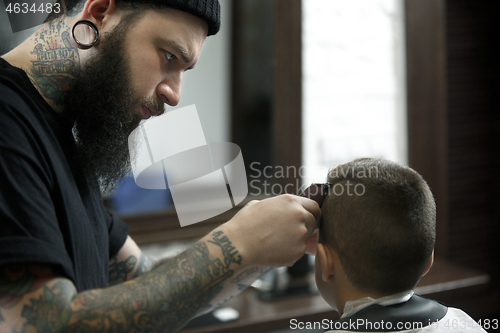 Image of Children hairdresser cutting little boy against a dark background.