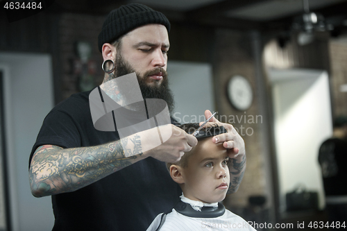 Image of Children hairdresser cutting little boy against a dark background.