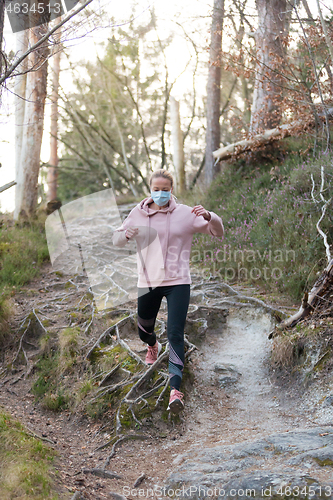 Image of Corona virus, or Covid-19, is spreading all over the world. Portrait of caucasian sporty woman wearing a medical protection face mask while running in nature.