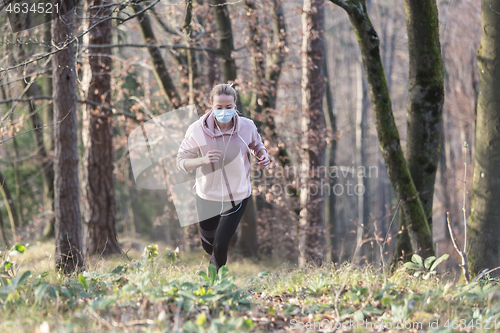 Image of Corona virus, or Covid-19, is spreading all over the world. Portrait of caucasian sporty woman wearing a medical protection face mask while running in nature.