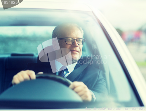 Image of happy senior businessman driving car