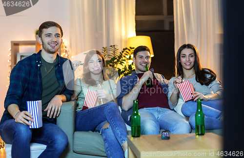 Image of friends with beer and popcorn watching tv at home