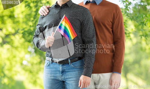 Image of close up of happy male couple with gay pride flags