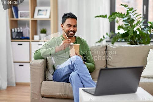 Image of indian man with laptop eating takeout food at home