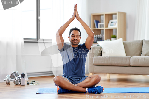 Image of indian man meditating in lotus pose at home