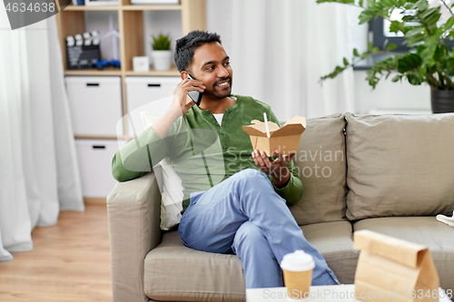 Image of smiling indian man eating takeaway food at home