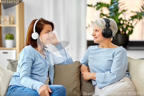 Image of senior mother and adult daughter with headphones