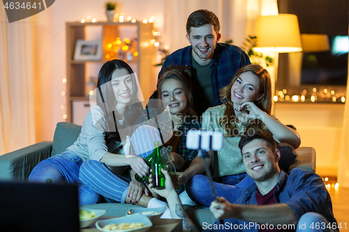 Image of friends taking picture by selfie stick at home