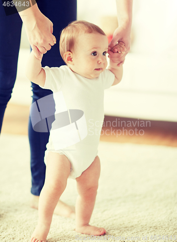 Image of happy baby learning to walk with mother help