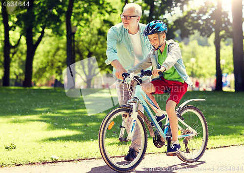 Image of grandfather and boy with bicycle at summer park