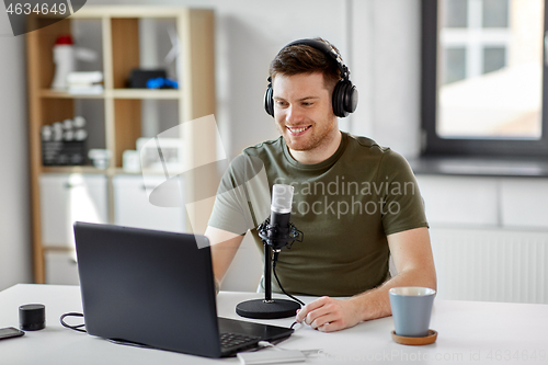 Image of man with laptop and microphone at home office