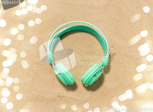 Image of earphones on summer beach sand