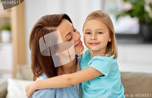 Image of little daughter hugging her mother on sofa at home