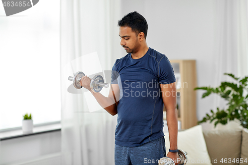 Image of indian man exercising with dumbbells at home