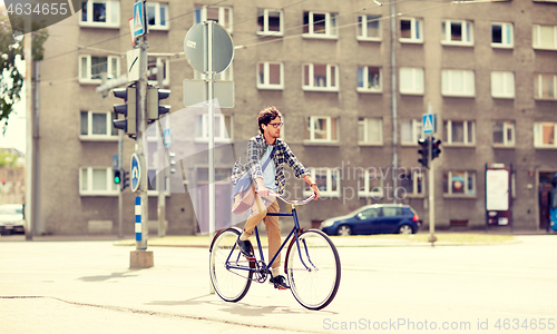 Image of young hipster man with bag riding fixed gear bike