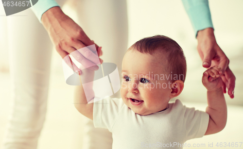 Image of happy baby learning to walk with mother help