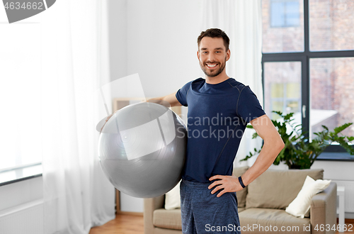 Image of man exercising with fitness ball at home