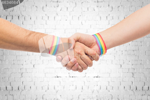 Image of hands with gay pride wristbands make handshake