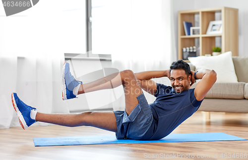 Image of indian man making abdominal exercises at home