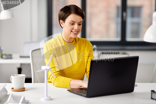 Image of happy businesswoman with laptop working at office