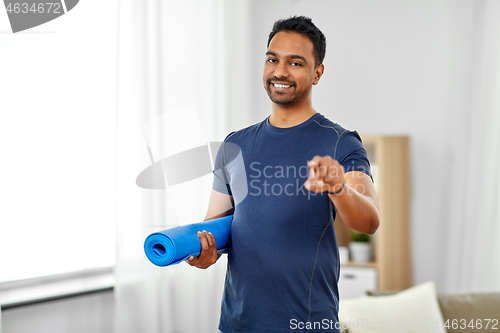 Image of smiling indian man with exercise mat at home