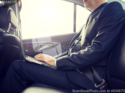 Image of senior businessman with laptop driving in car