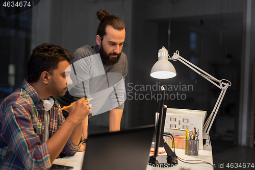 Image of creative team with computer working late at office