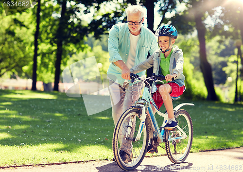 Image of grandfather and boy with bicycle at summer park