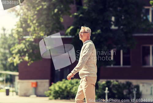 Image of senior man walking along summer city street