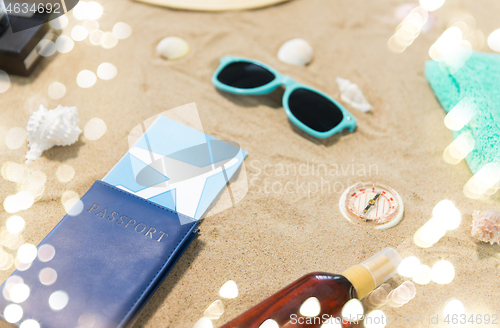 Image of travel tickets, camera and hat on beach sand