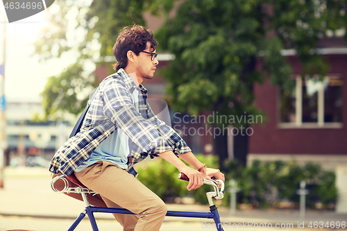 Image of young hipster man with bag riding fixed gear bike